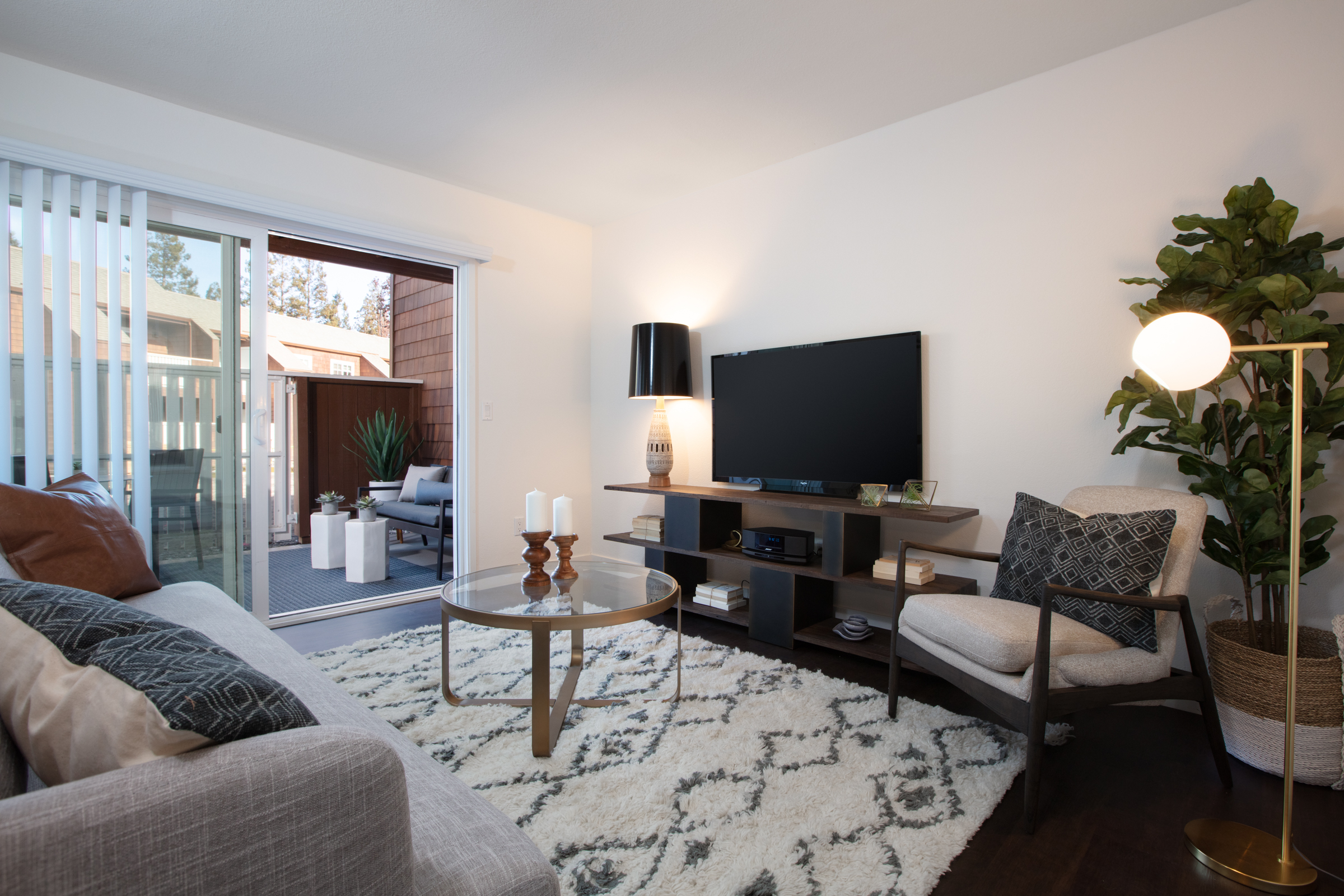 Apartments In Sunnyvale, CA With In-Unit Washer And Dryer - The Grove Garden - A Living Room With A Soft Gray Sofa, Glass Coffee Table, And Sliding Glass Doors.