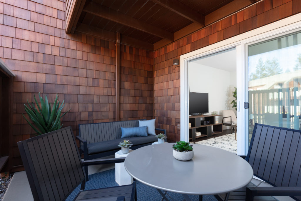 Apartments Near Levi's Stadium In Sunnyvale, CA - The Grove Garden - An Outdoor Patio With Dark Gray Outdoor Sofa, Small Potted Succulents, And A Wood-Paneled Ceiling.