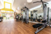 Well lit gym, with work out equipment, wood flooring and sliding glass doors.