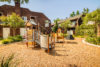 Playground surrounded by green landscaping and apartments.