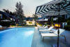 Twilight swimming pool with sun loungers and blue and white striped umbrellas.
