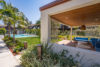 Grassy pool area with palm trees and covered cabana building.