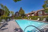 Rectangular shaped gated pool with lounge seating surrounded by 2 story apartment buildings.
