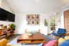 Large coffee table in lounge area with TV, board games and bird art on wall.