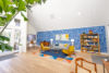 White ceilinged room, wood flooring with colorful lounge seating table white chairs and book case.